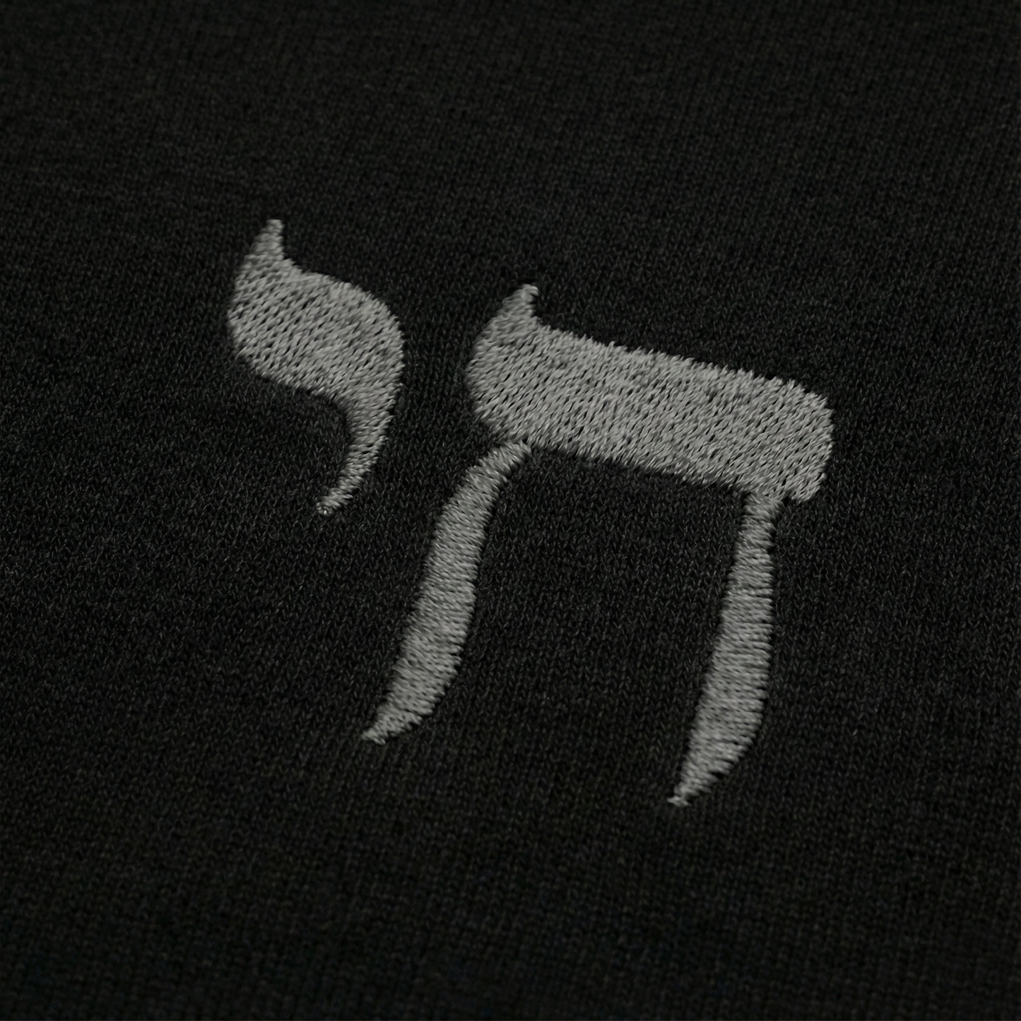 Embroidered letter 'Chai' on a black background