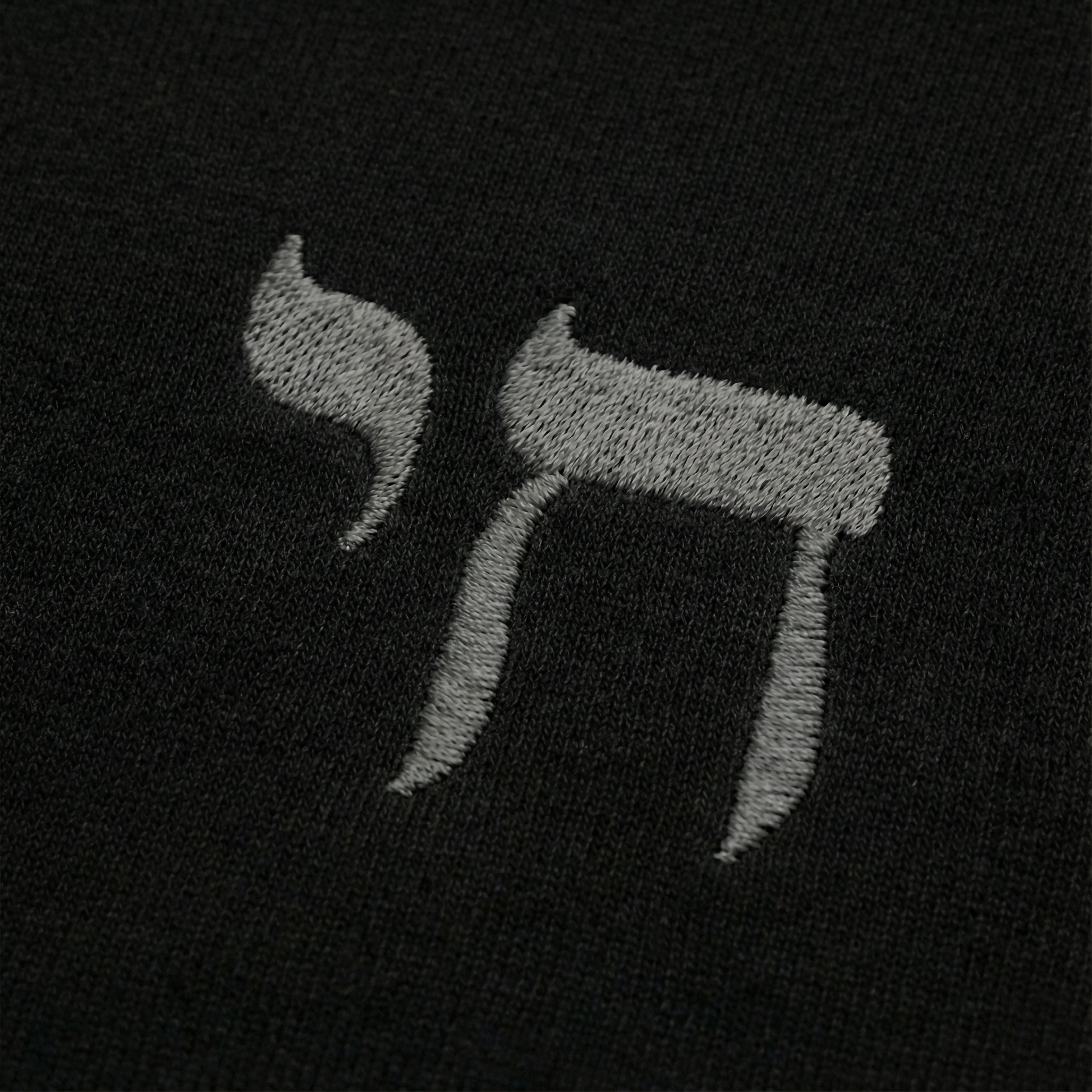 Embroidered letter 'Chai' on a black background