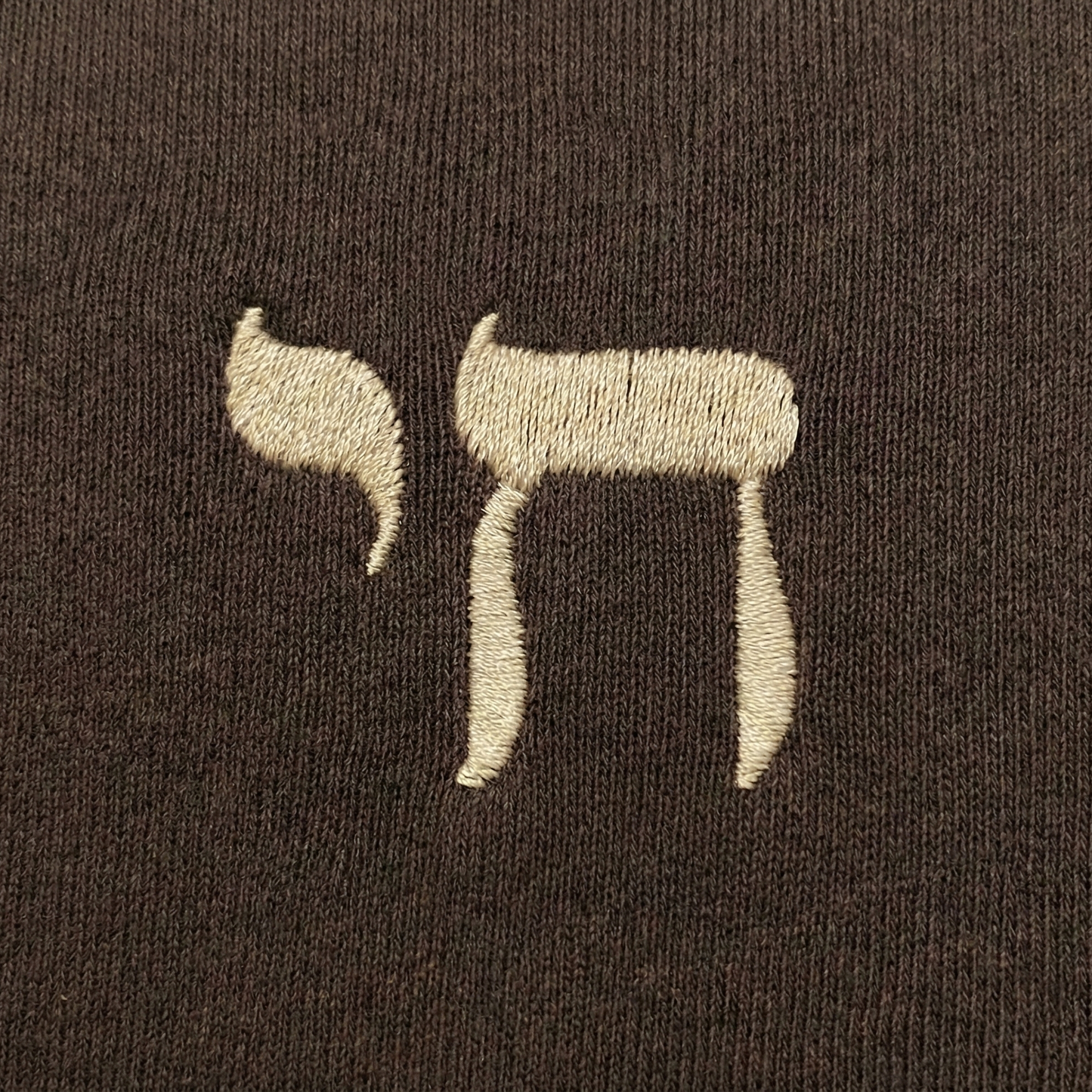 Embroidered Hebrew "Chai" on a brown fabric background