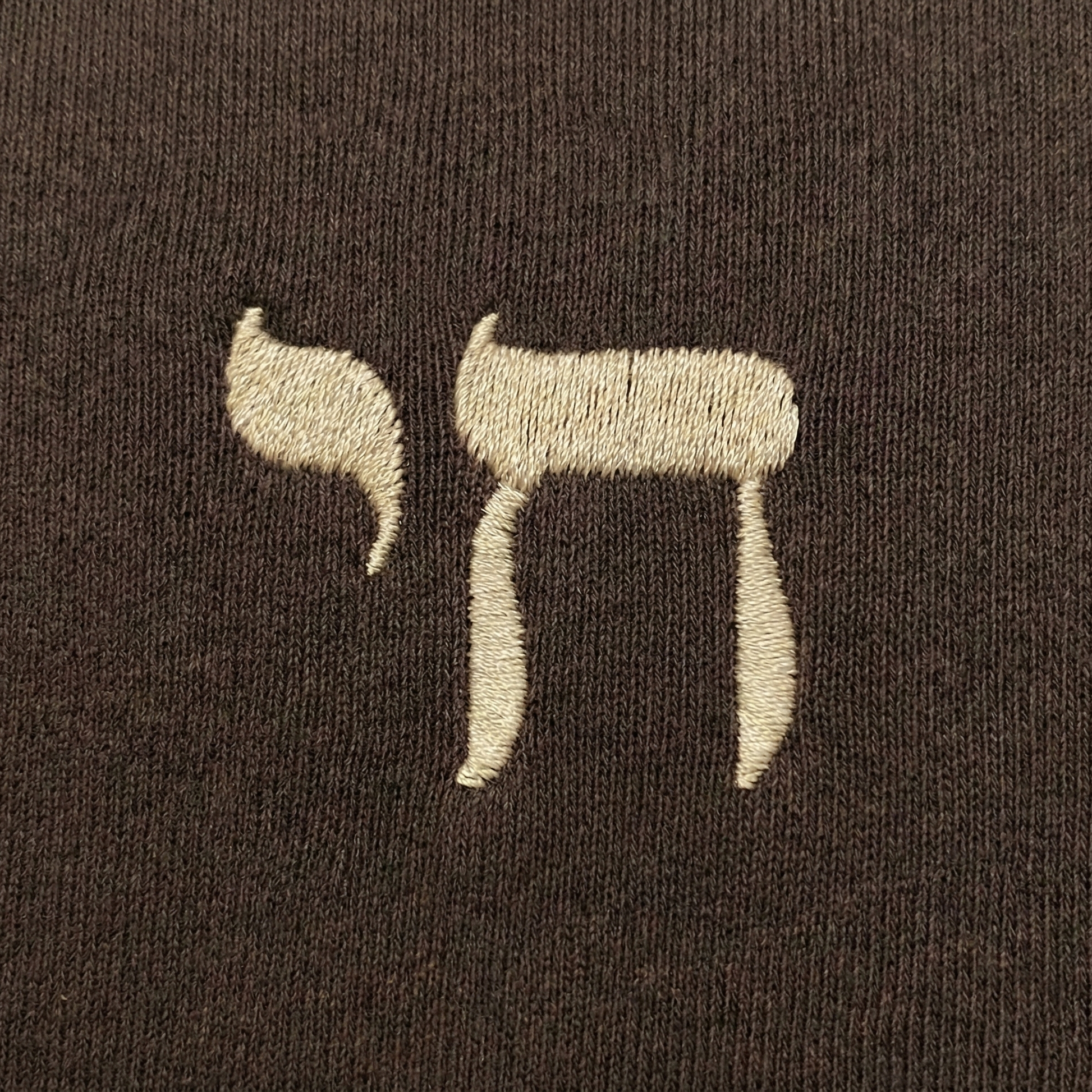 Embroidered Hebrew "Chai" on a brown fabric background