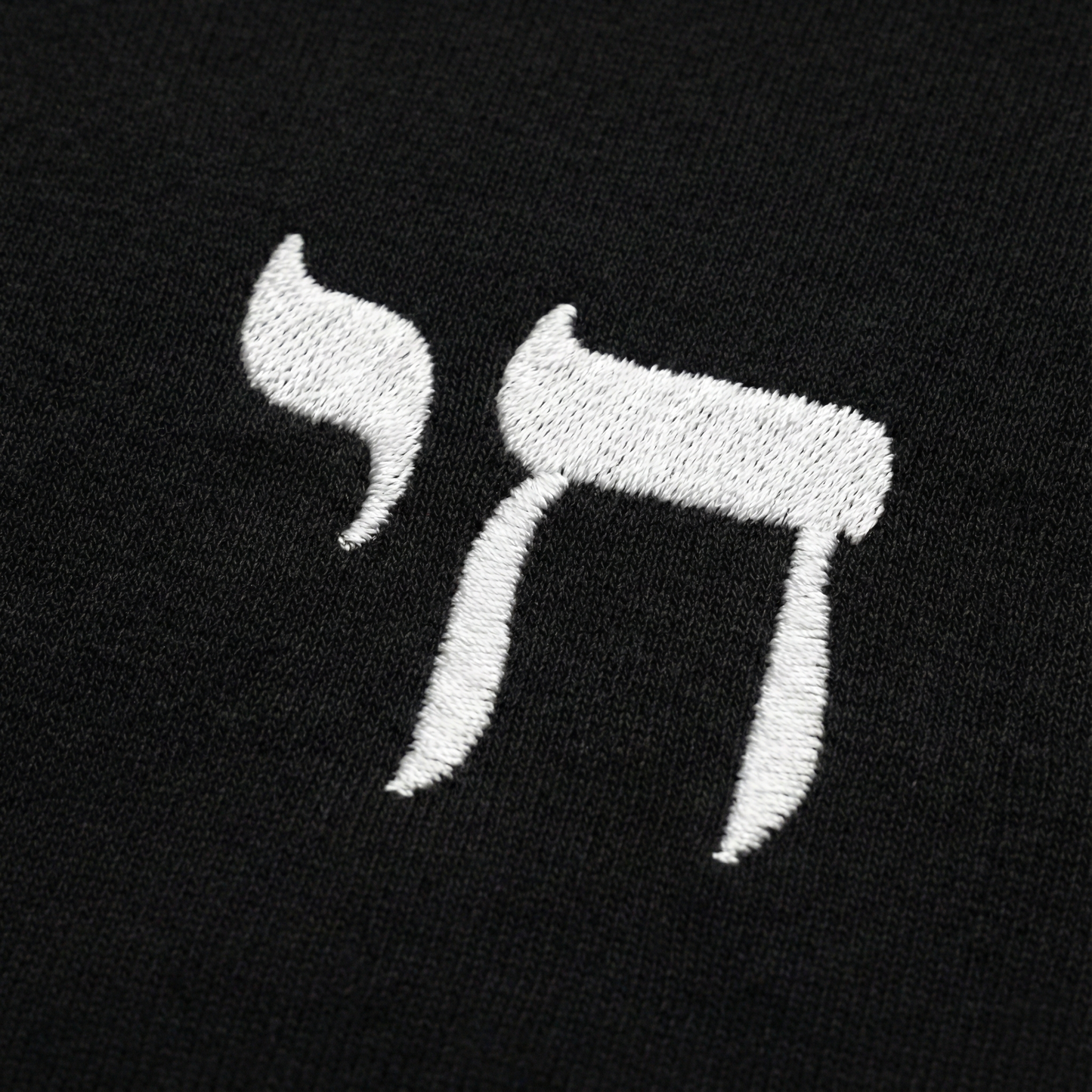 Embroidered letter 'Chai' in white on a black background