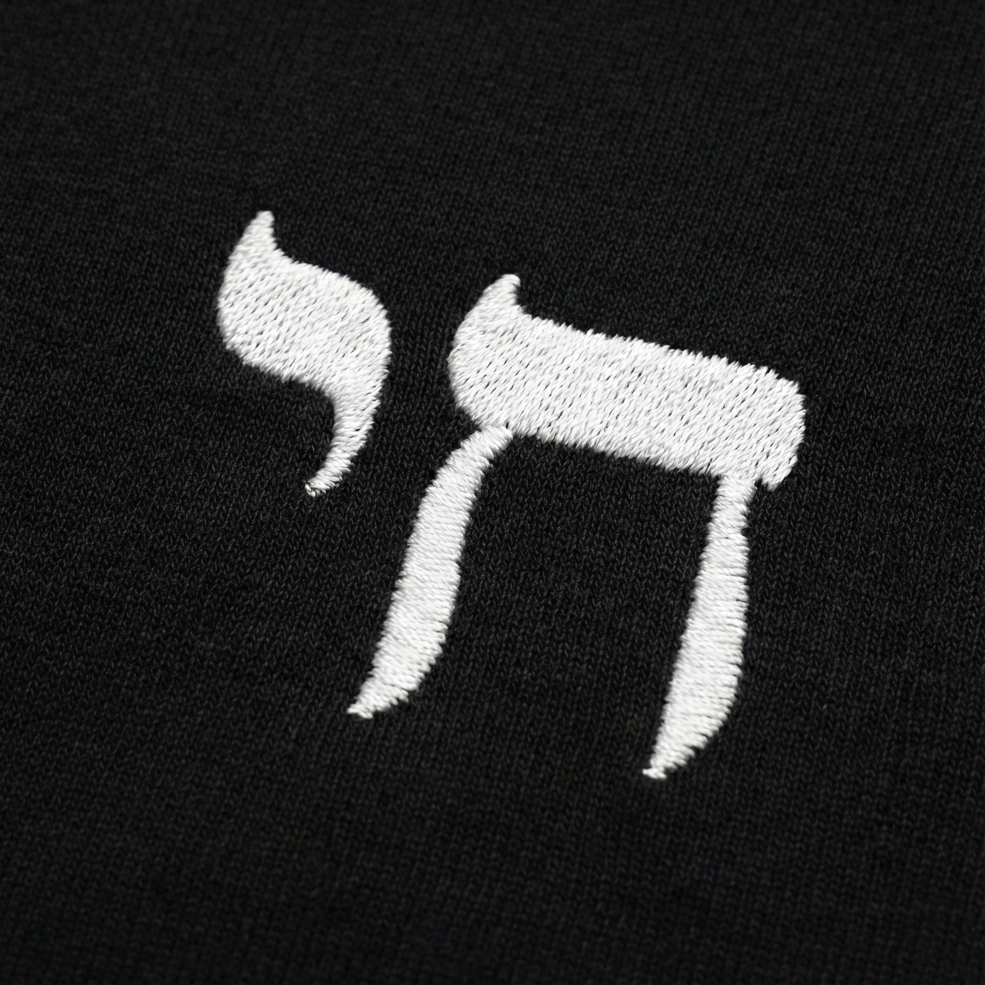Embroidered letter 'Chai' in white on a black background